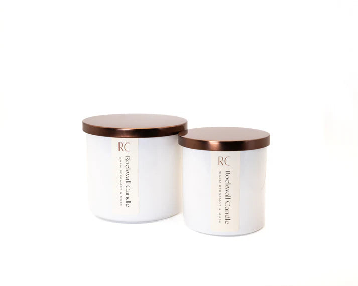 Two white candles with bronze lids on a white background