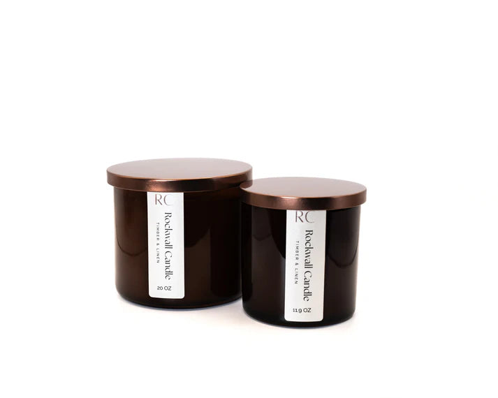 Two black candles with bronze lids on a white background