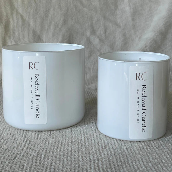 Two white candles with 'Rockwall Candle' labels on a textured surface