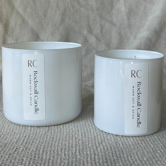 Two white candles with 'Rockwall Candle' labels on a textured surface