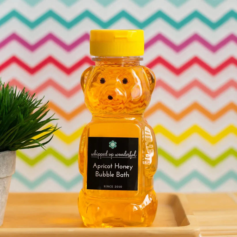 Bear-shaped bottle of Apricot Honey Bubble Bath with a colorful zigzag pattern in the background